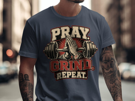 T-shirt graphic with praying hands between barbells, stating "PRAY GRIND REPEAT."
