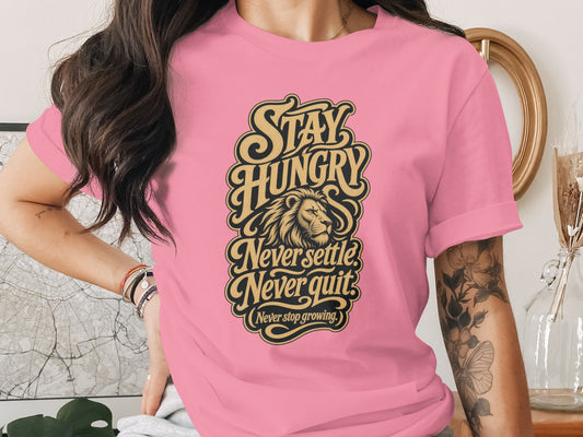 Pink t-shirt with "Stay Hungry," "Never Settle," "Never Quit," and "Never Stop Growing" text and lion graphic.