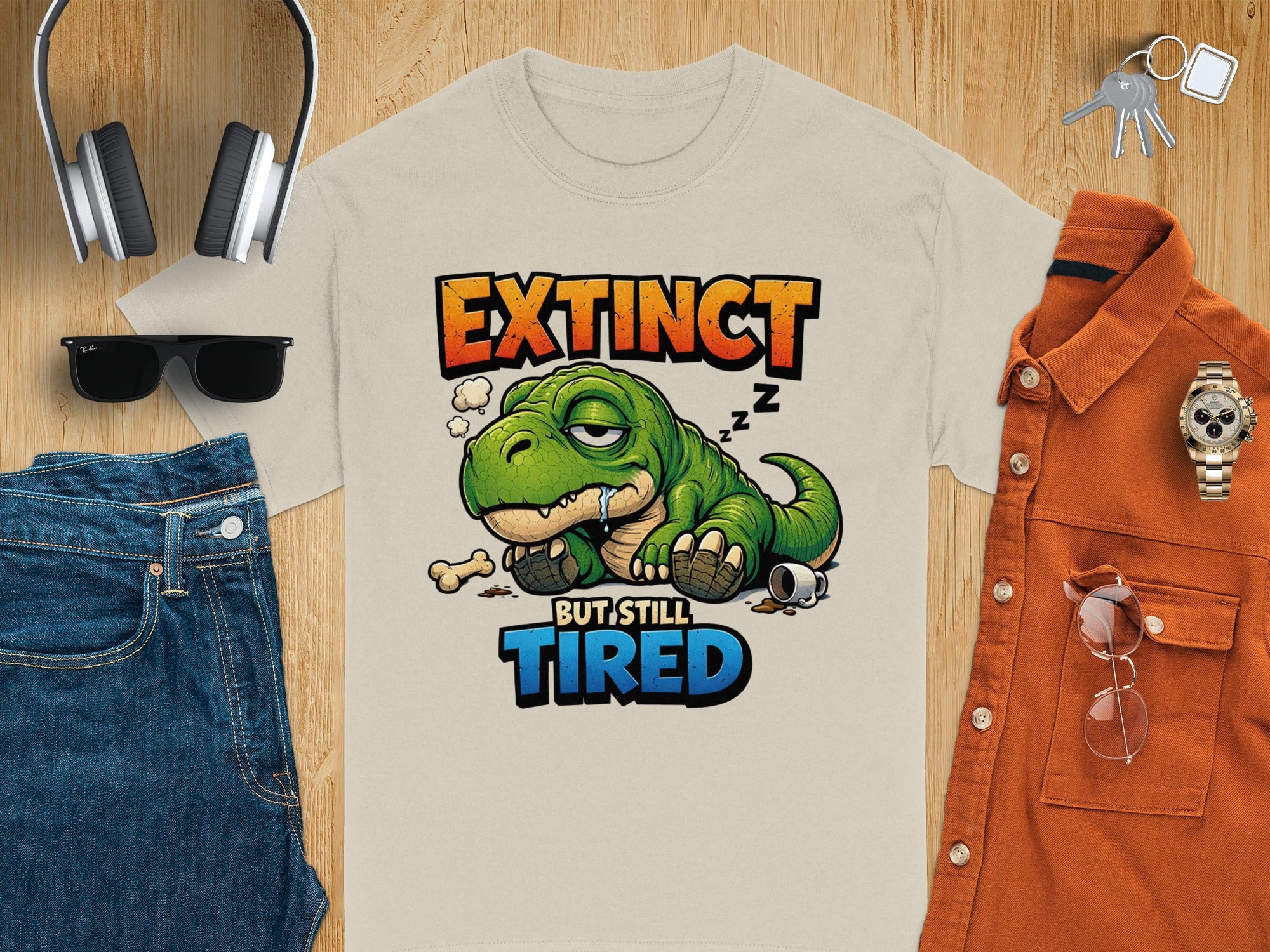 T-shirt graphic: Extinct but still tired text with a green dinosaur sleeping.