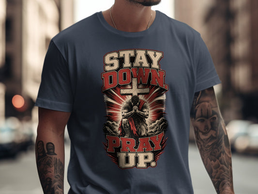 Graphic on t-shirt with text "STAY DOWN PRAY UP" and praying figure.