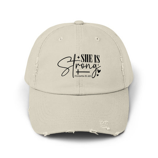 Distressed beige baseball cap with "SHE IS Strong" and "Proverbs 31:25" text.