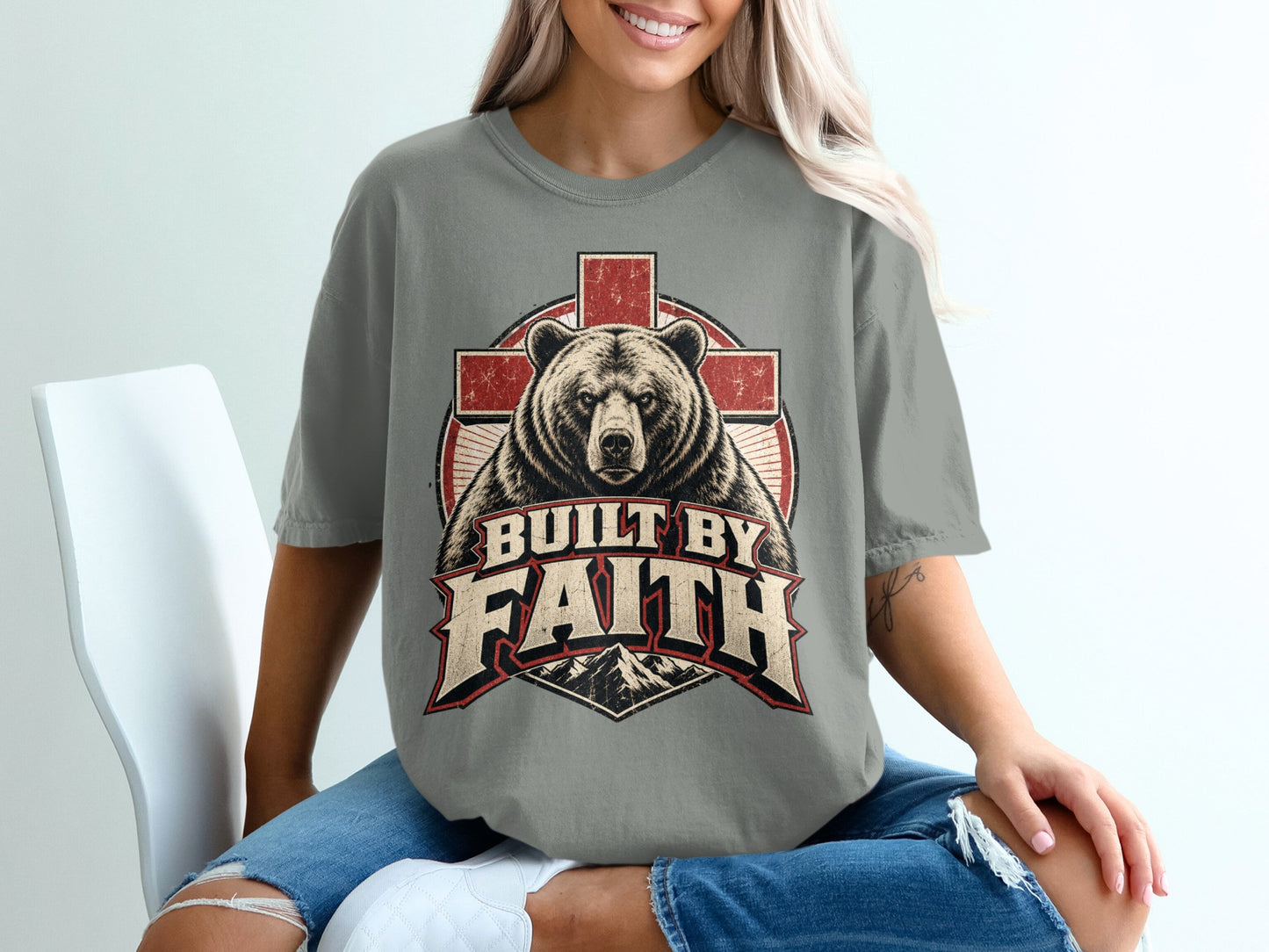 T-shirt graphic of bear and cross with text "BUILT BY FAITH" and mountains.