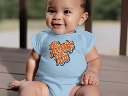 Baby wearing a light blue bodysuit with orange text saying "Kingdom Kid".