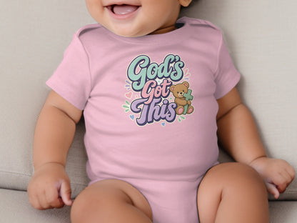 Pink baby onesie with "God's Got This" text and a teddy bear holding a cross.