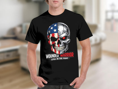 Black t-shirt with a skull graphic featuring American flag and metallic elements. Text reads "Wounded Warrior Still In The Fight".