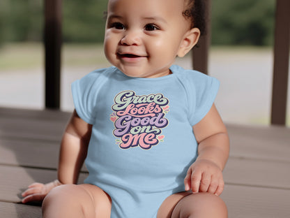 Baby in a light blue onesie with multi-colored text reading "Grace Looks Good on Me".