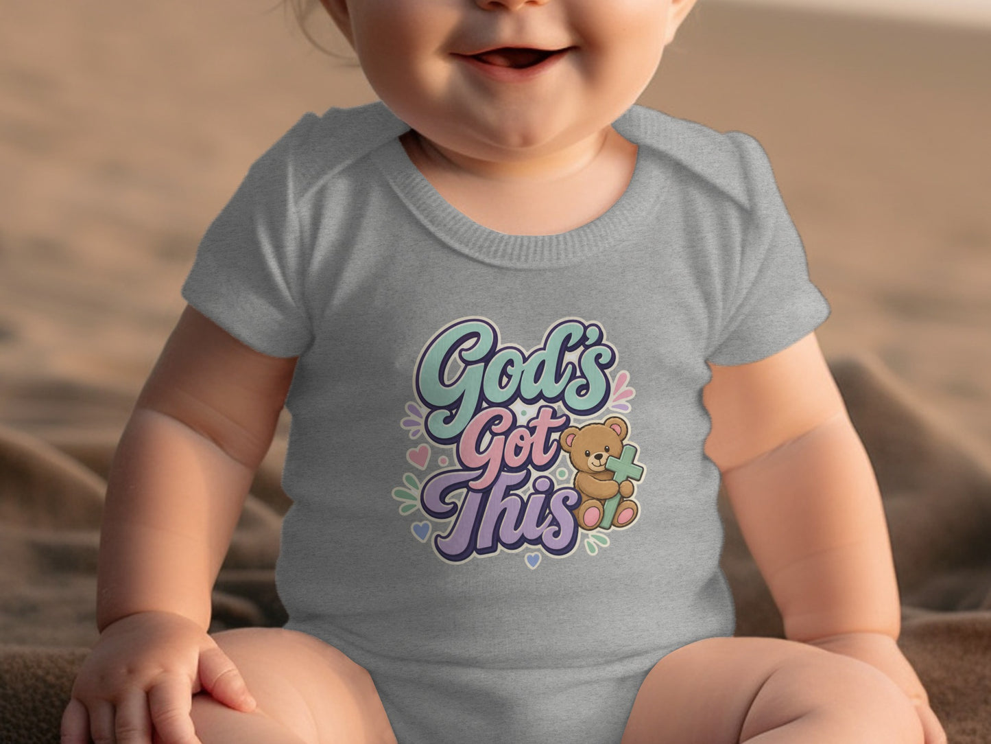 Gray baby onesie with "God's Got This" text and a teddy bear holding a cross.