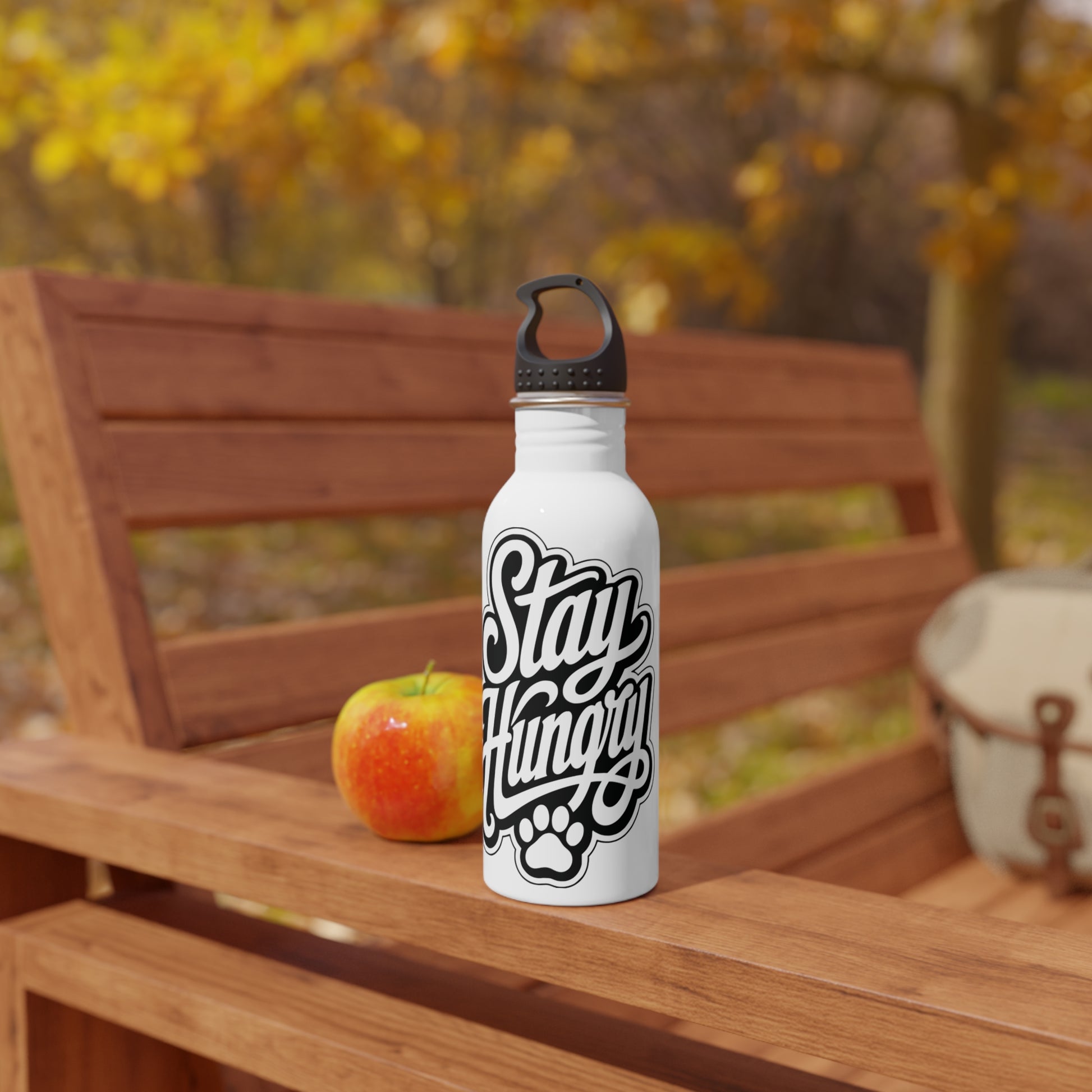 White water bottle with "Stay Hungry" text and paw print on a wooden bench.