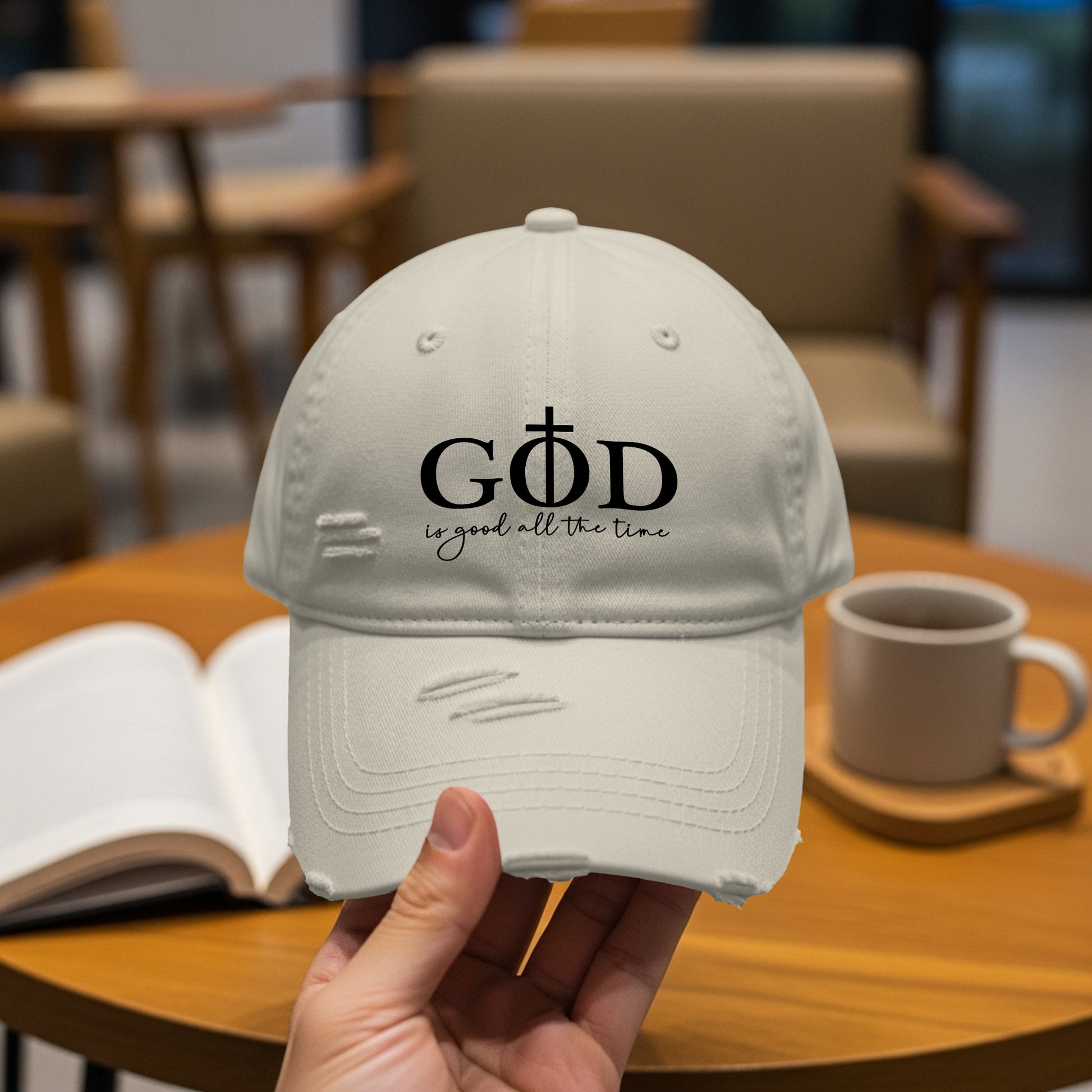 Distressed light-colored baseball cap with "GOD is good all the time" text.
