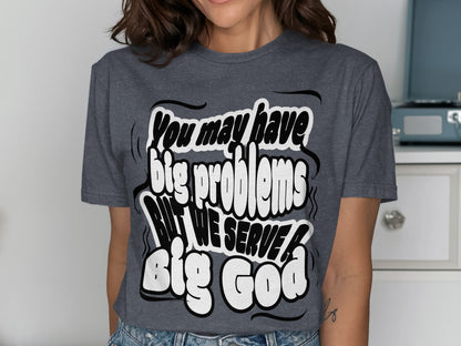Dark gray t-shirt with white bubble text that reads "You may have big problems BUT WE SERVE Big God".