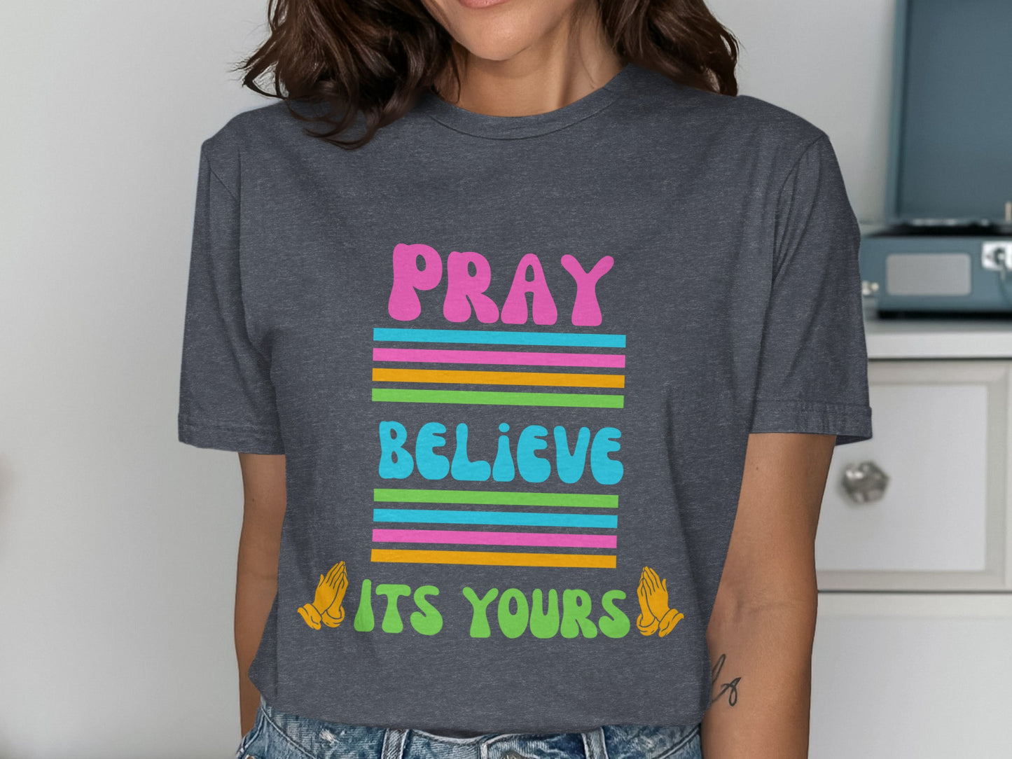 Dark gray t-shirt with colorful text: "PRAY BELIEVE ITS YOURS" and praying hands.