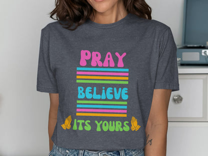 Dark gray t-shirt with colorful text: "PRAY BELIEVE ITS YOURS" and praying hands.