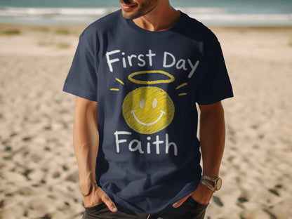 Navy t-shirt with chalk-style text "First Day Faith" and a yellow halo smiley face.