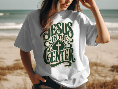 White t-shirt with green text "JESUS IS THE CENTER" and a cross inside a house.