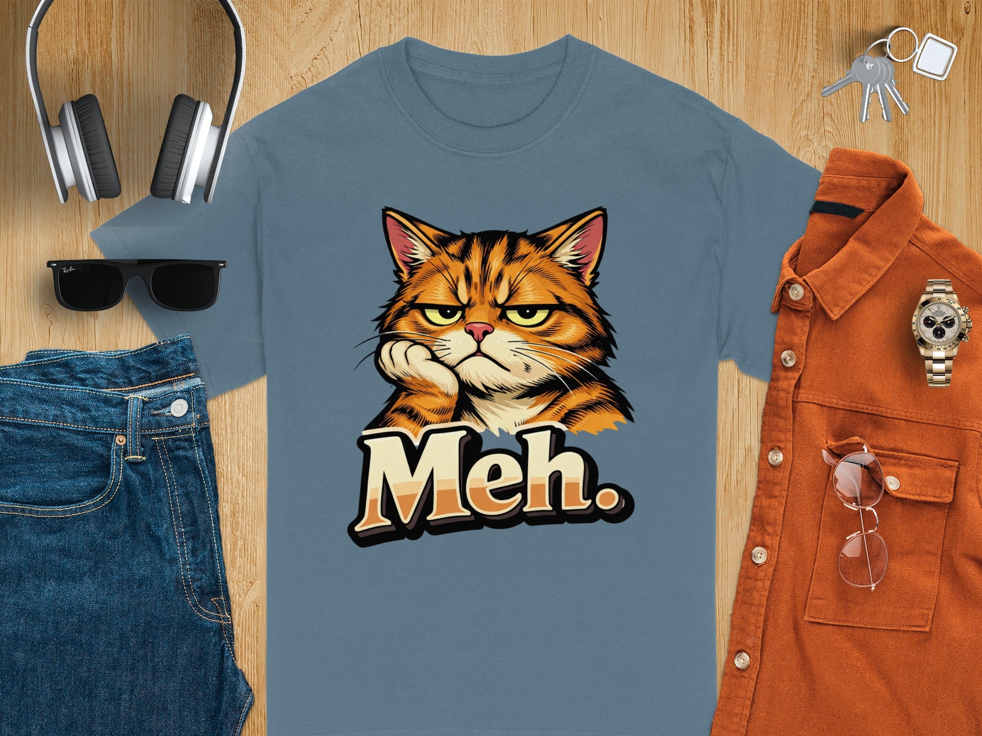 Blue t-shirt with cartoon cat and "Meh." text, styled with jeans and accessories.