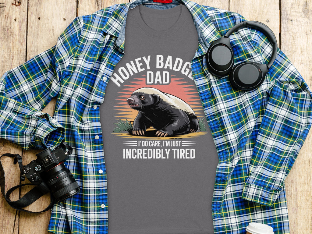 Grey t-shirt with honey badger wearing headphones and text: Honey Badger Dad, I Do Care, I'm Just Incredibly Tired.
