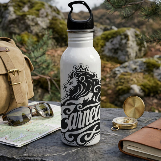White water bottle with black lion crown and text "Earned" on outdoor table.