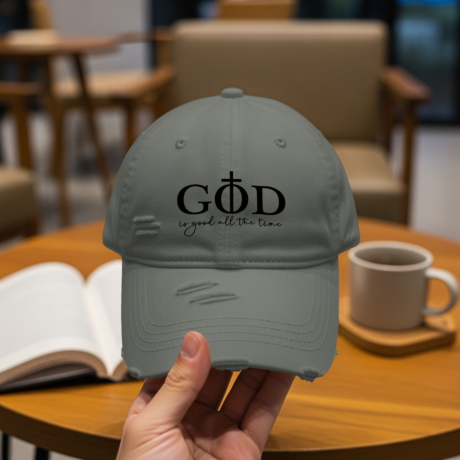 Distressed gray baseball cap with "GOD is good all the time" text and a cross.