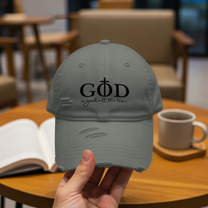 Distressed gray baseball cap with "GOD is good all the time" text and a cross.