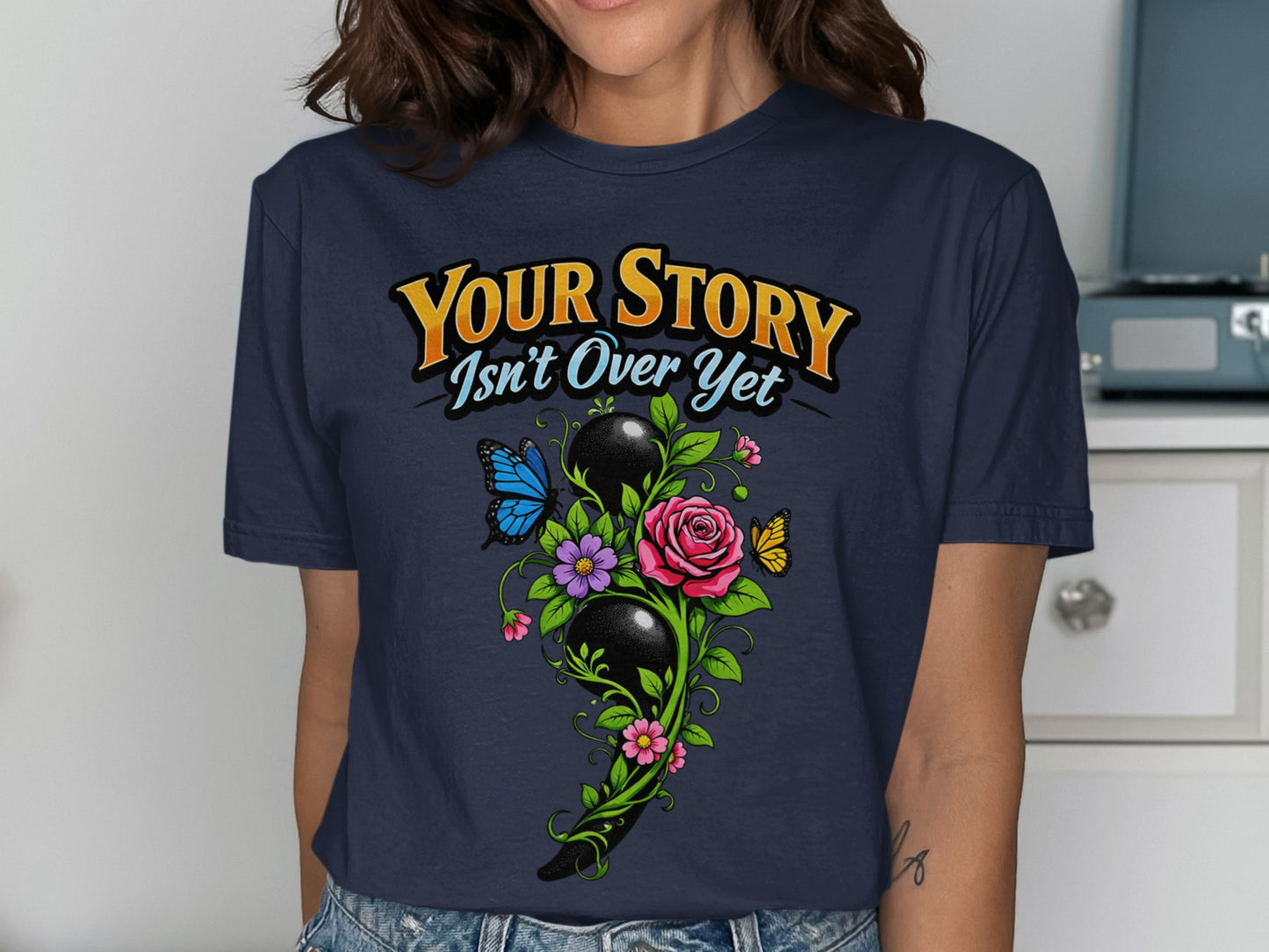 Navy t-shirt with "Your Story Isn't Over Yet" text and semicolon floral design.