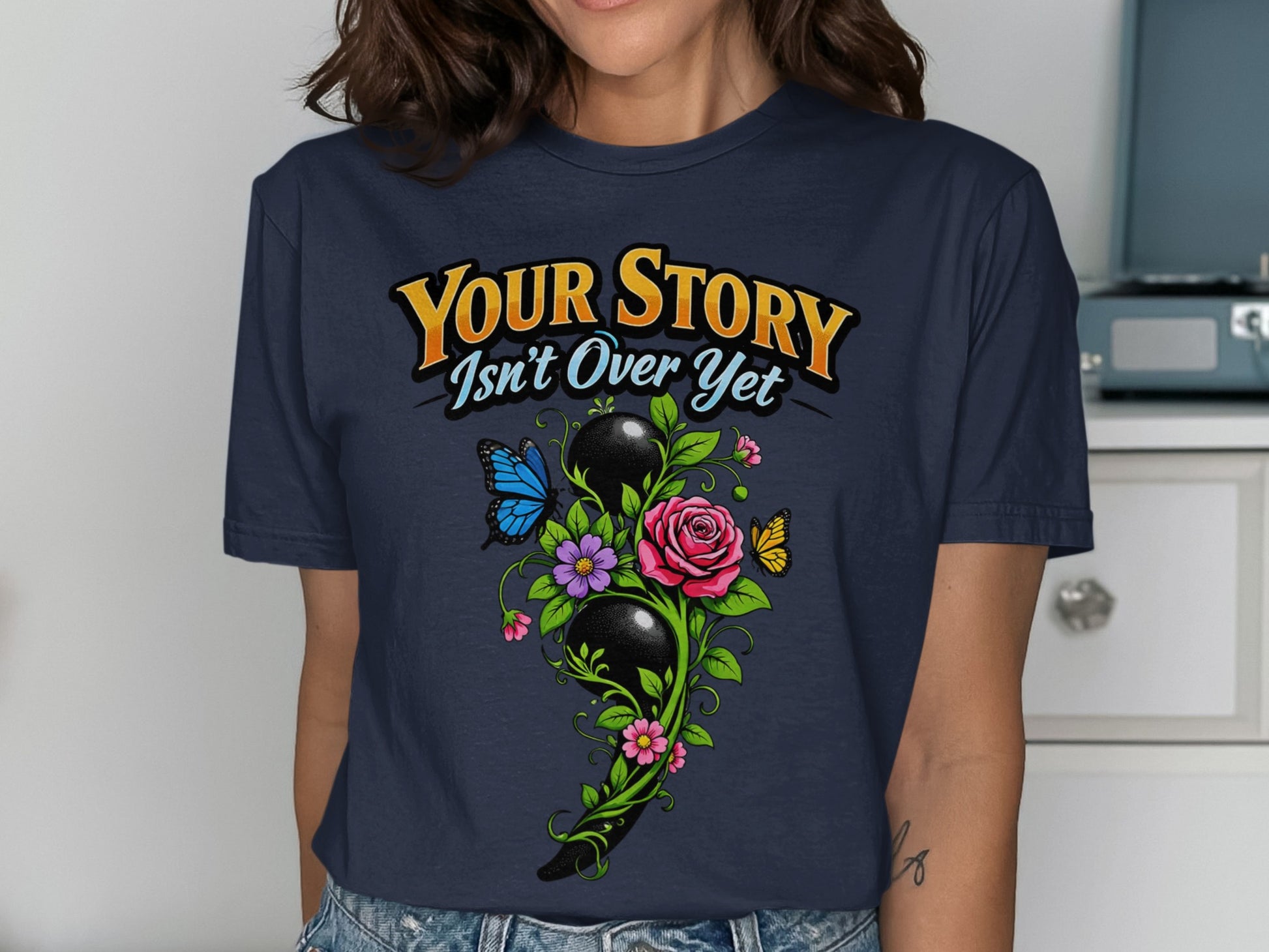 Navy t-shirt with "Your Story Isn't Over Yet" text and semicolon floral design.