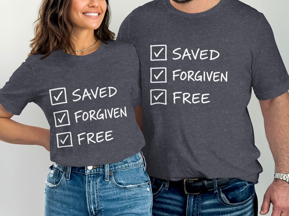 Two people wear dark grey t-shirts with white text and checkmarks: "Saved," "Forgiven," "Free."