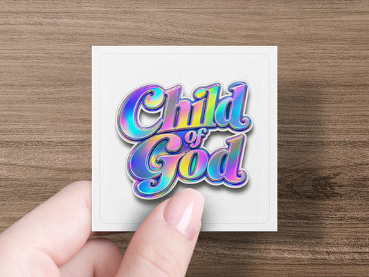"Child of God" text with iridescent colors on a white square card held by a hand.