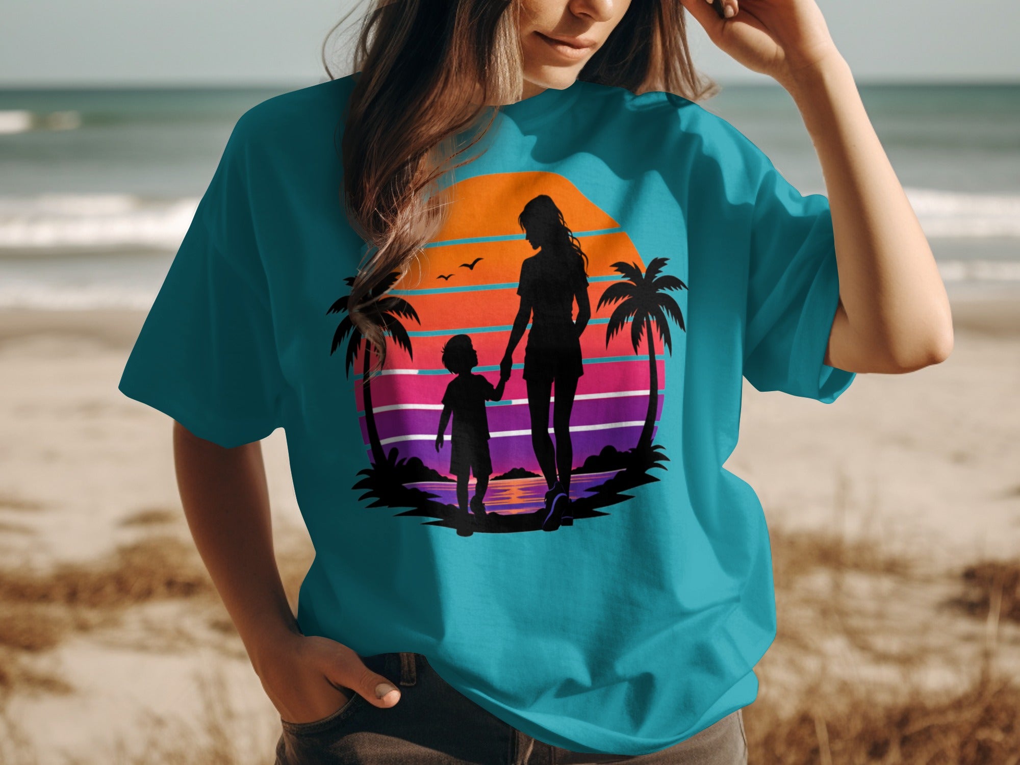 Woman wearing teal t-shirt with mother and child silhouette and sunset graphic.