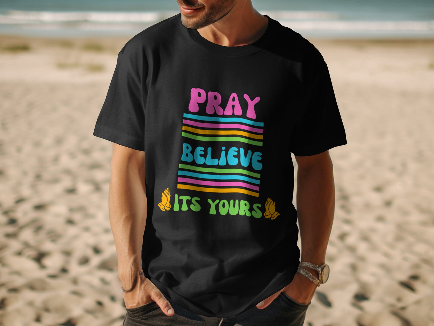 Black t-shirt with colorful "PRAY BELIEVE ITS YOURS" text and praying hands graphics.