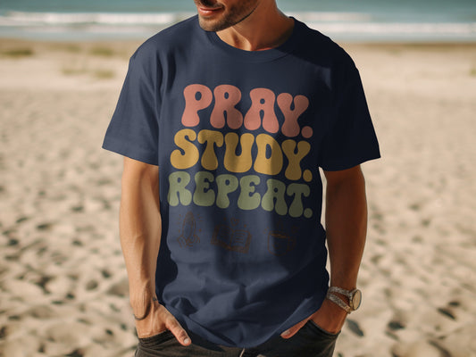 Navy t-shirt with "Pray. Study. Repeat." text and icons of praying hands, book, and coffee cup.