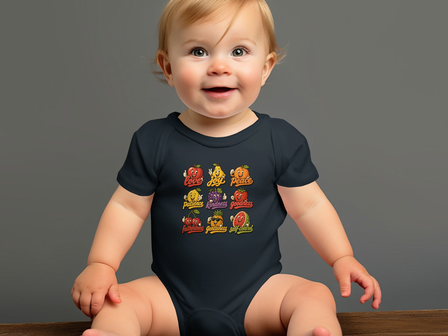 Baby wearing dark onesie with fruits depicting virtues: love, joy, peace, patience, kindness, goodness, faithfulness, gentleness, self-control.