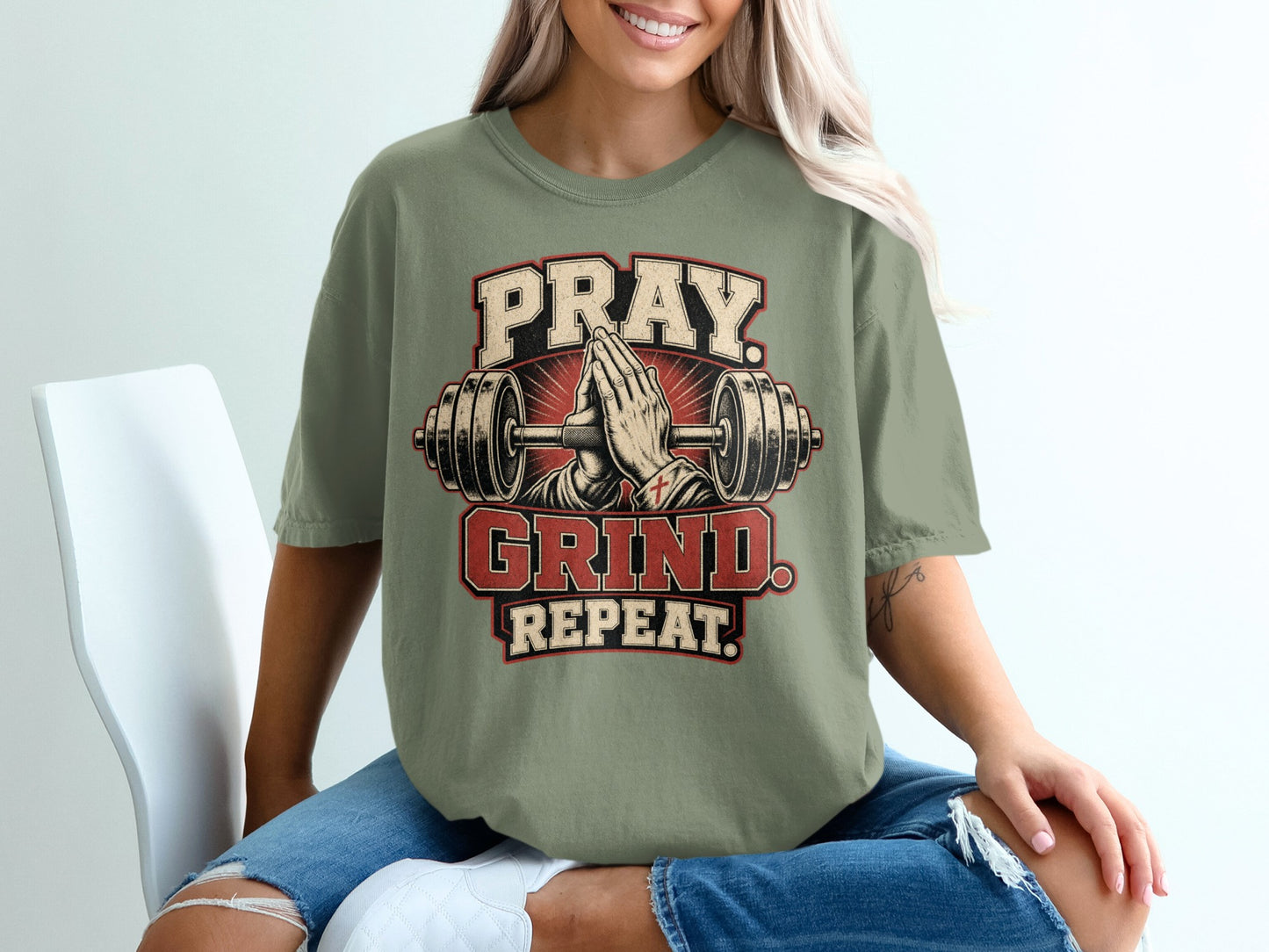 Olive green t-shirt with "Pray. Grind. Repeat." graphic and praying hands and barbell.