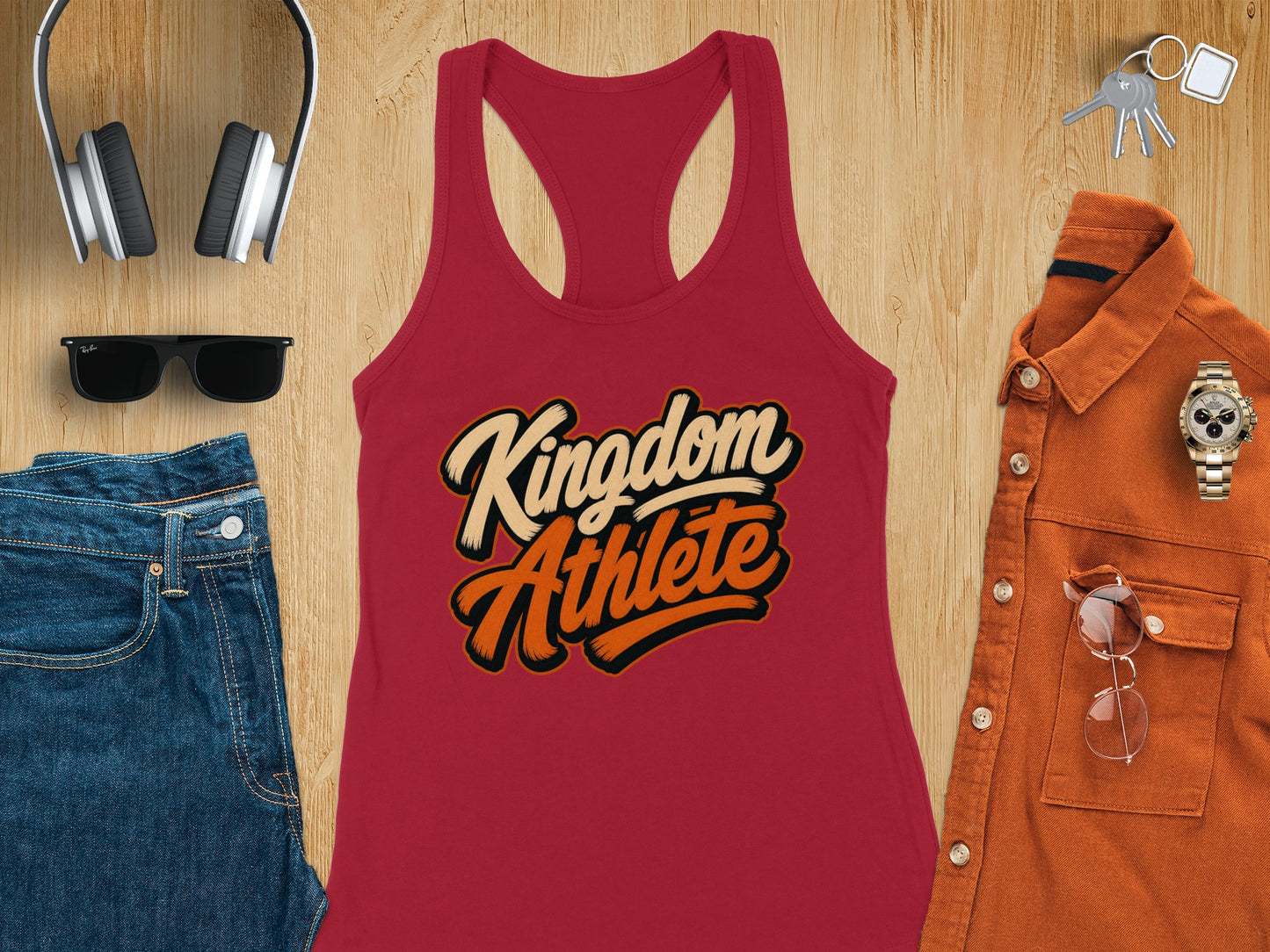 Red tank top with "Kingdom Athlete" text, alongside jeans, headphones, sunglasses, jacket, and keys.