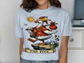 Goose wearing jester hat, carrying bag on stick, with sun and mountains, text "THE FOOL".