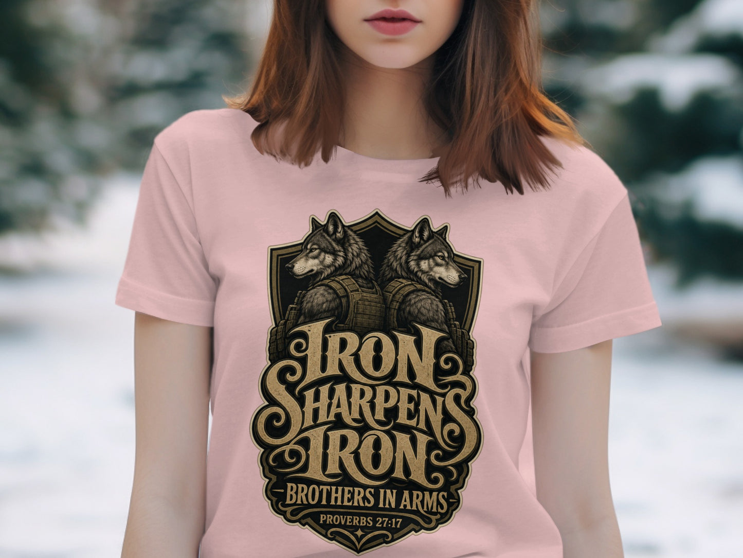 Pink t-shirt with a shield design featuring two wolves and text "Iron Sharpens Iron Brothers in Arms".