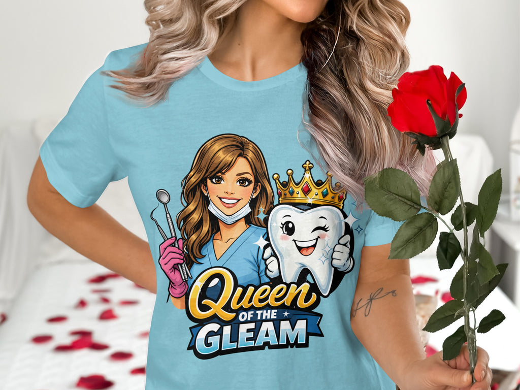 Light blue t-shirt with dental graphic: woman with mask, dental tools, and a crowned tooth. Text reads "Queen of the Gleam."