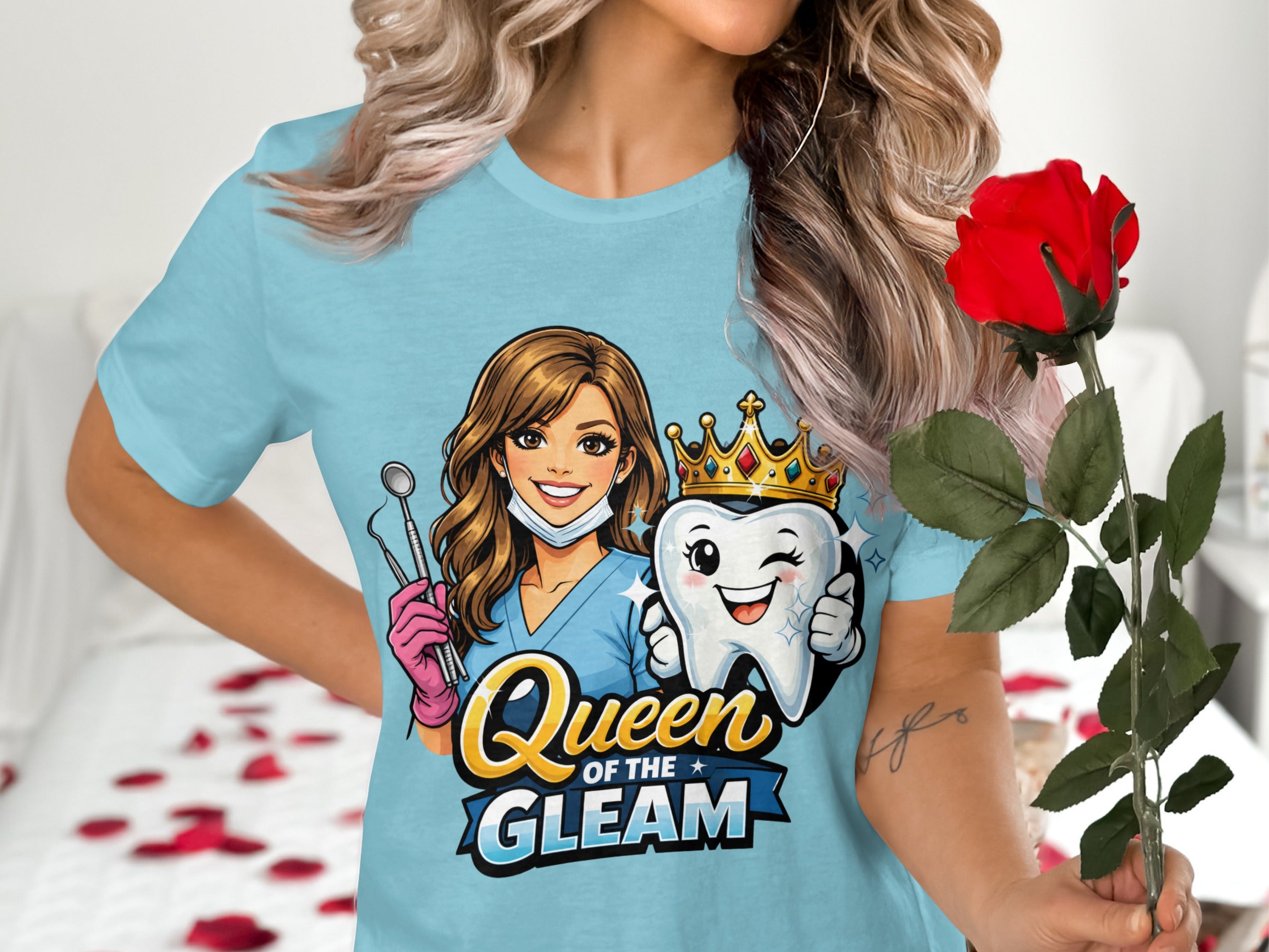 Light blue t-shirt with dental graphic: woman with mask, dental tools, and a crowned tooth. Text reads "Queen of the Gleam."