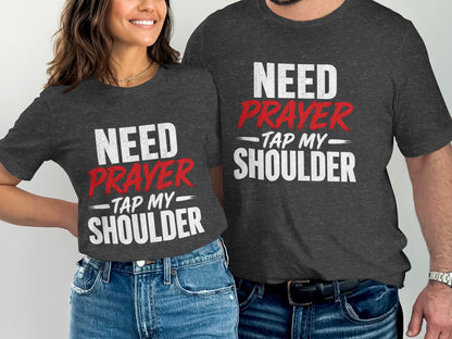 Two people wearing matching dark grey t-shirts with "NEED PRAYER TAP MY SHOULDER" text.