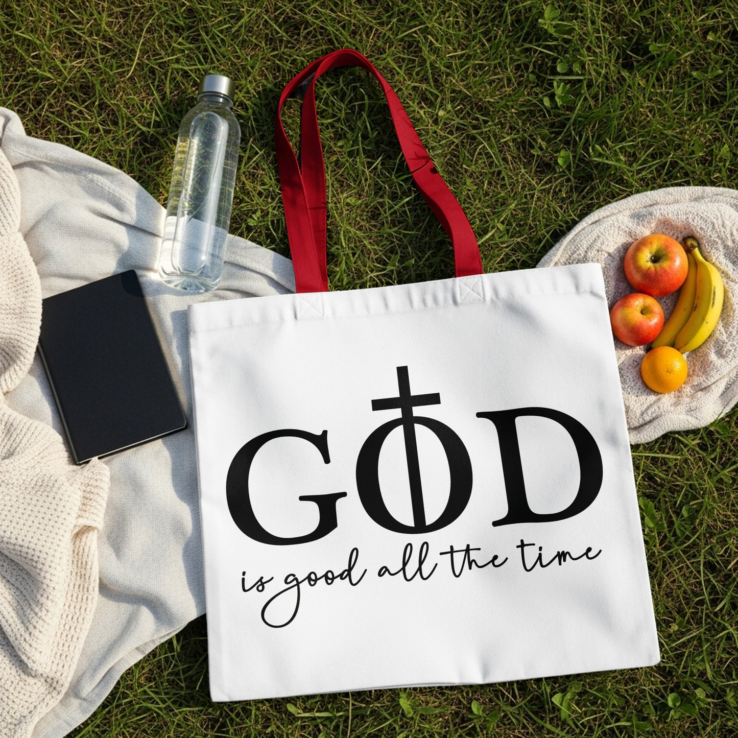 White tote bag with "God is good all the time" text and a cross.