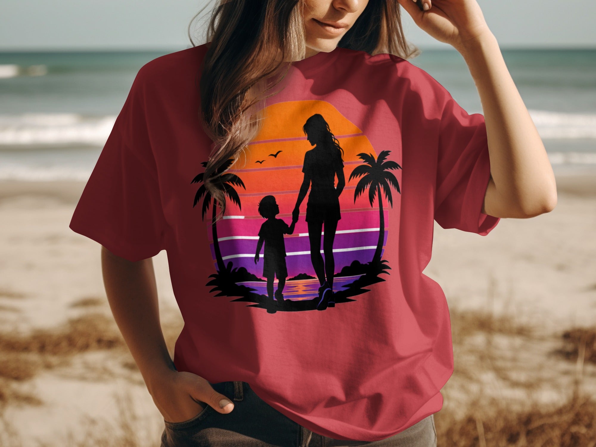 T-shirt with a sunset silhouette of a mother and child on a beach.