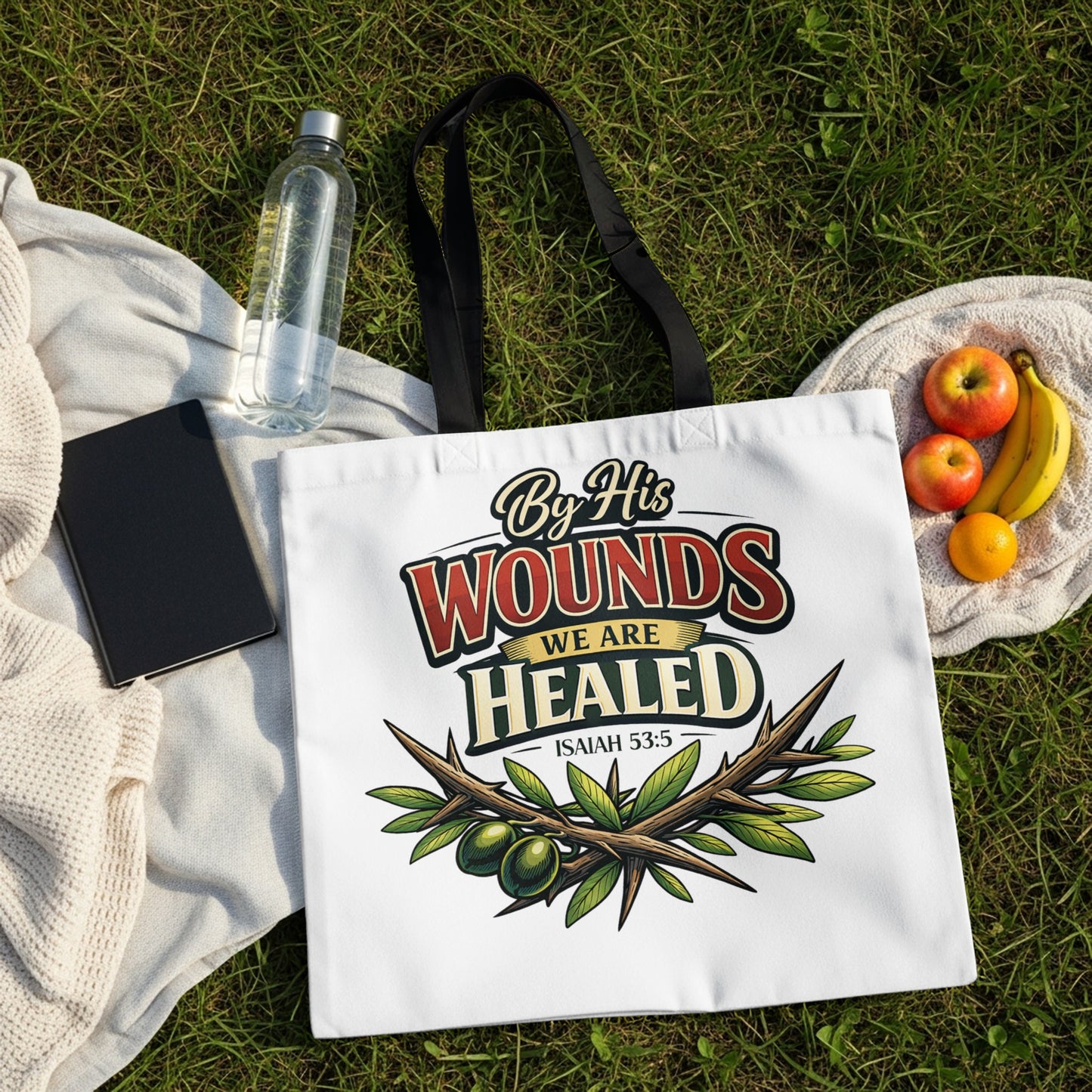 White tote bag with "By His Wounds We Are Healed Isaiah 53:5" text and olive branch graphic.