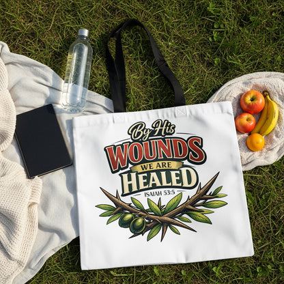 White tote bag with "By His Wounds We Are Healed Isaiah 53:5" text and olive branch graphic.