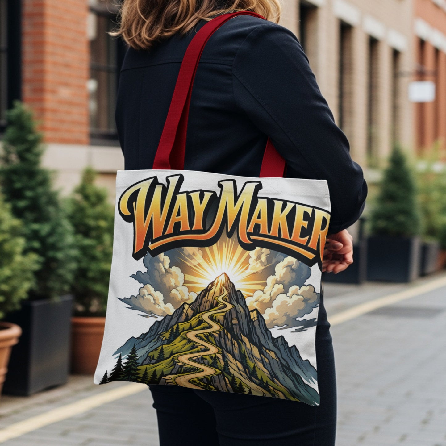 Tote bag with "Way Maker" text over a mountain road leading to a bright sun.