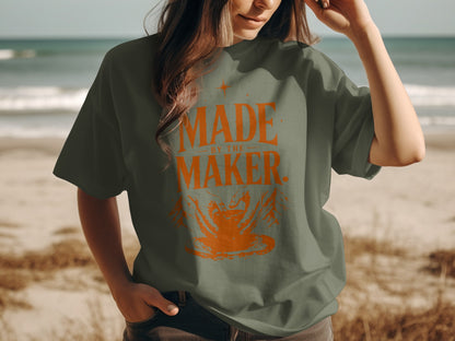 Green t-shirt with orange graphic text "MADE BY THE MAKER" and pottery image.