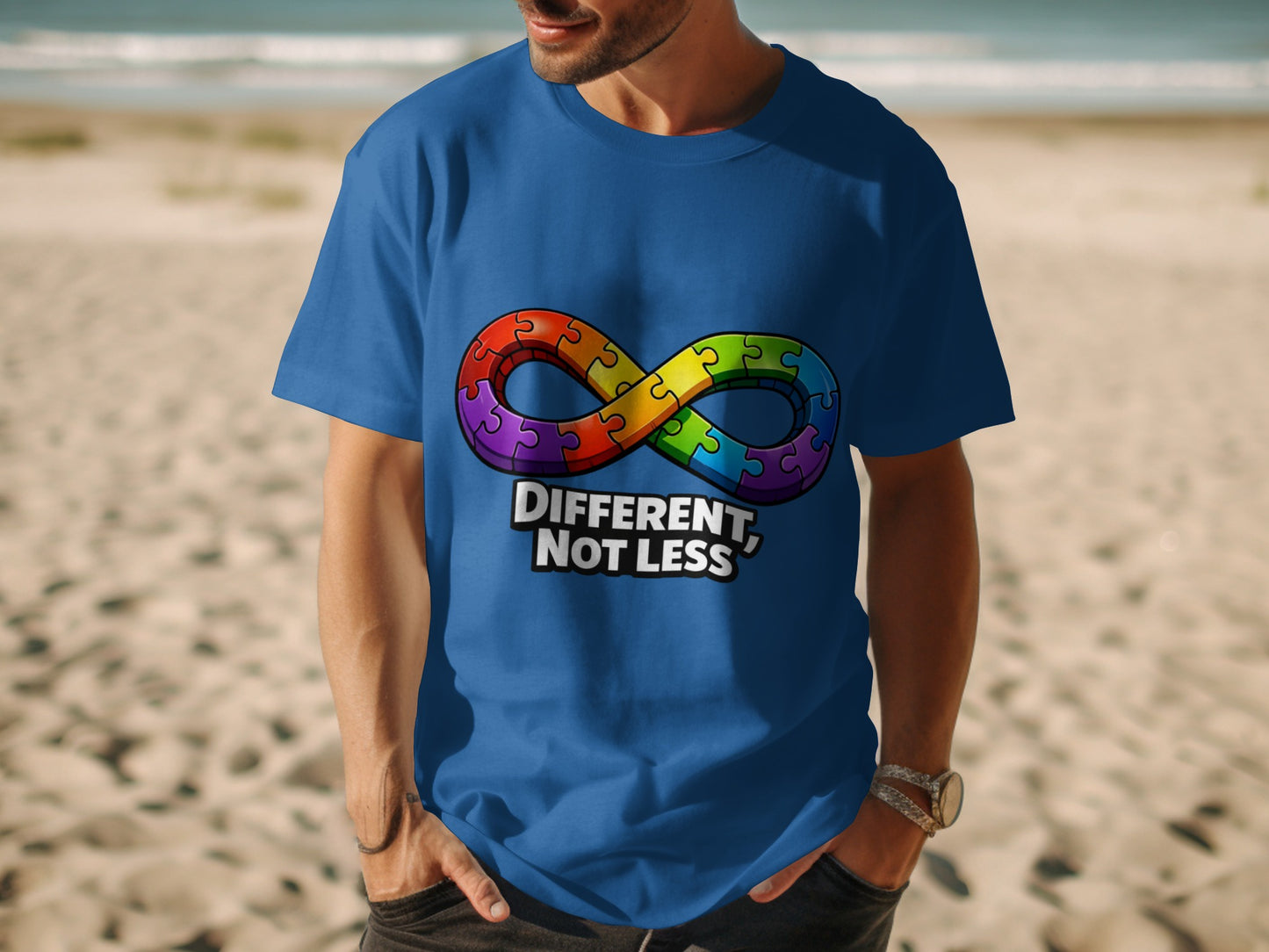 Blue t-shirt with rainbow infinity puzzle symbol and text "DIFFERENT, NOT LESS".