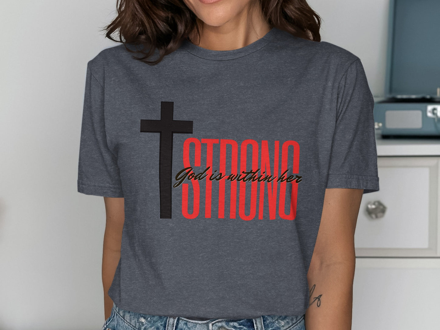 Dark grey t-shirt with black cross and red text saying "STRONG God is within her".