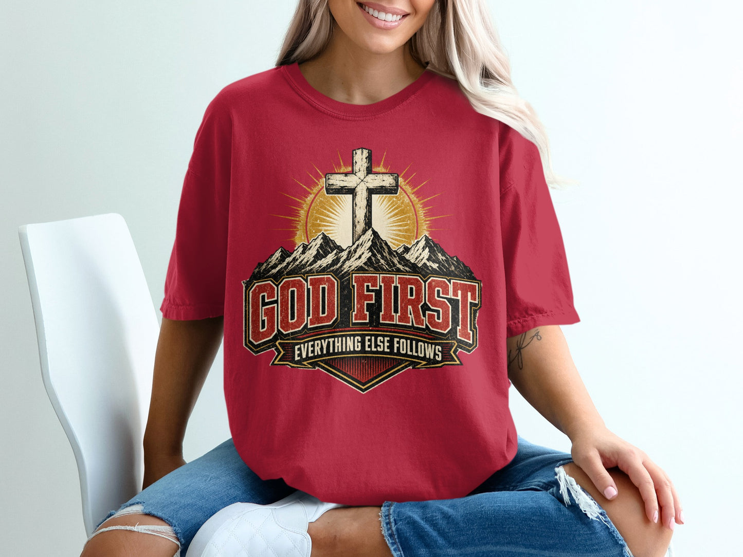 Red t-shirt with "GOD FIRST EVERYTHING ELSE FOLLOWS" text and cross on mountains.