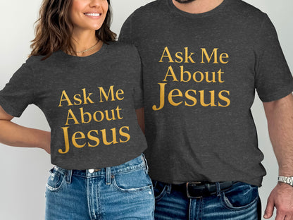 Two people wearing dark grey t-shirts with gold text that reads "Ask Me About Jesus."