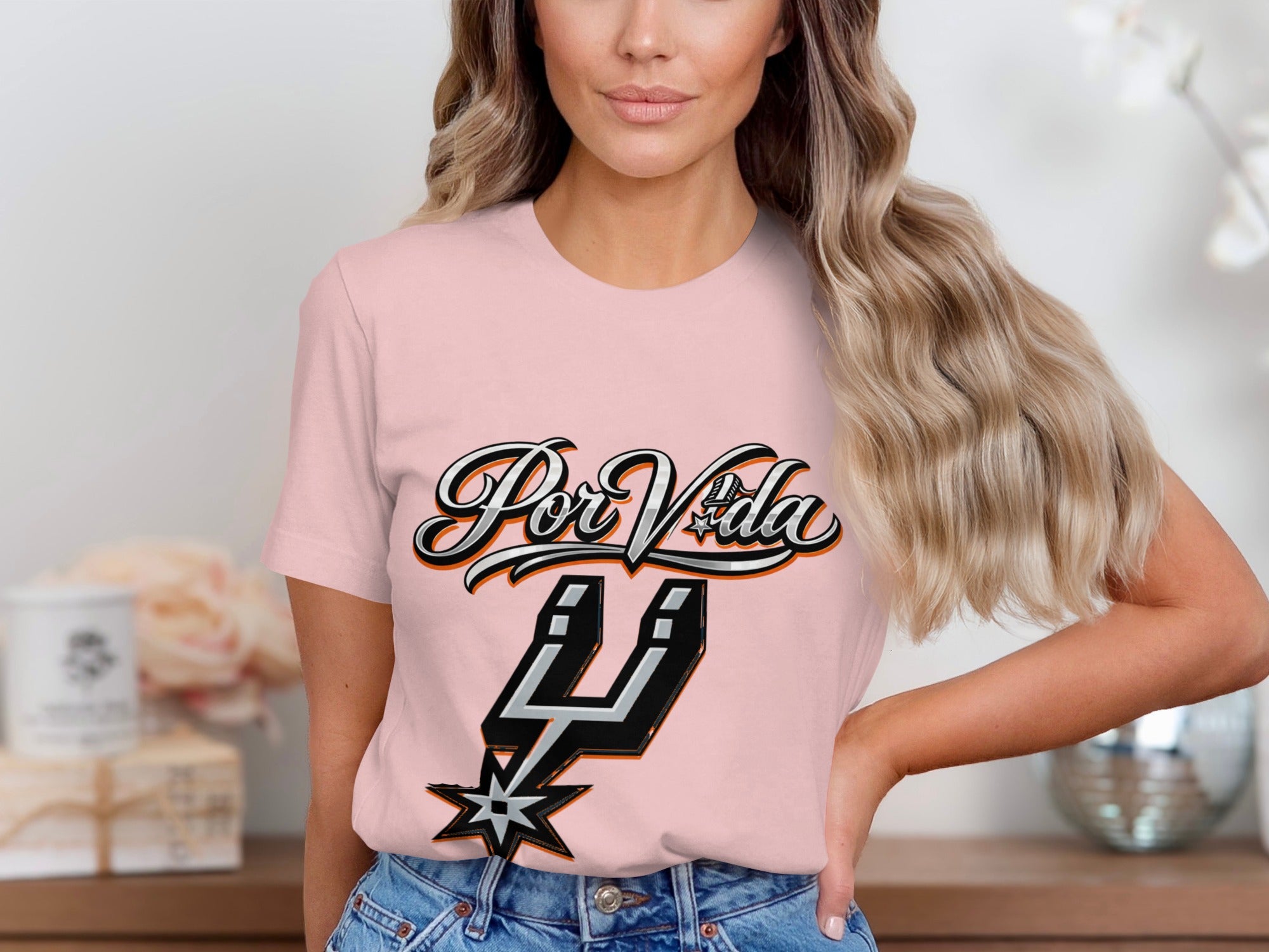 Pink t-shirt with black and orange "Por Vida" text and a Spurs logo.