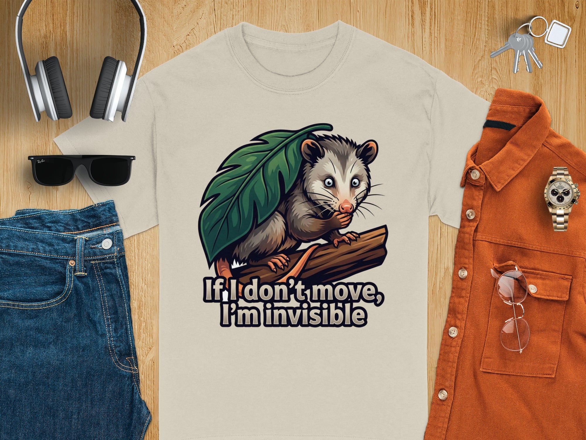 Opossum illustration on a tan t-shirt reads "If I don't move, I'm invisible".